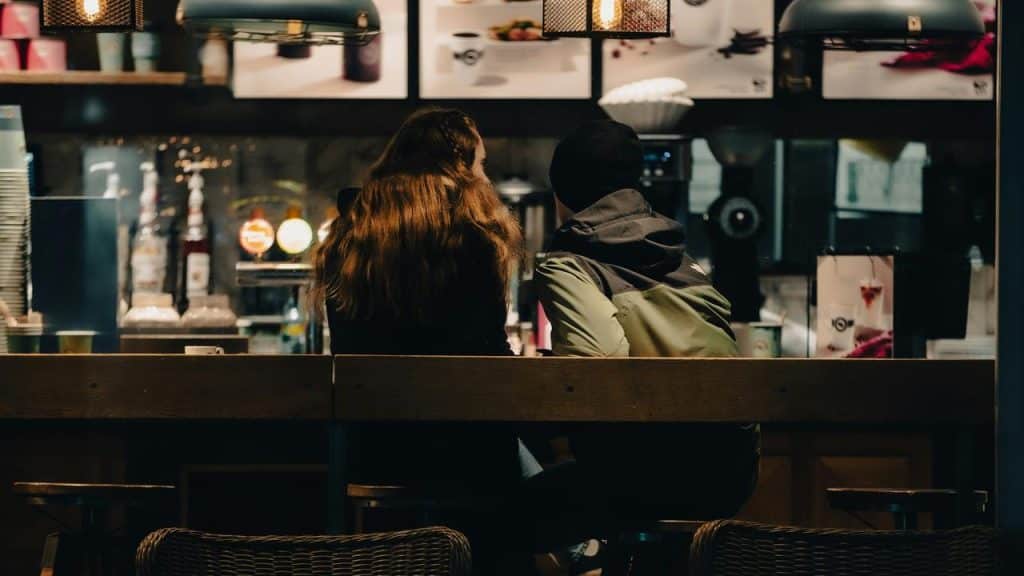 A couple sitting at a café counter, viewed from behind.