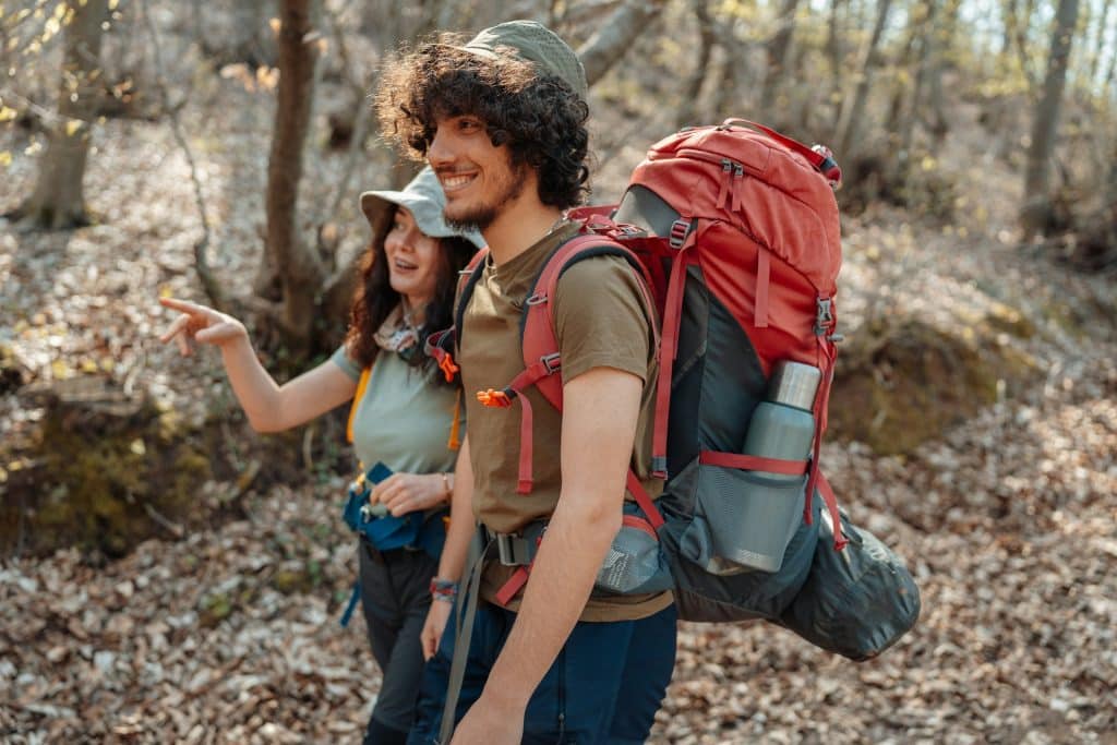 The couple is walking through the woods.
