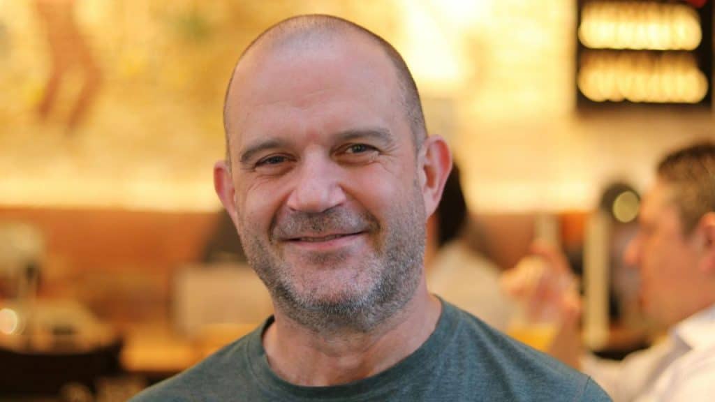 Smiling middle-aged man with a shaved head and light beard looking directly at the camera.