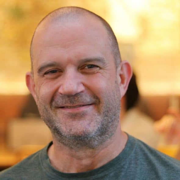Smiling middle-aged man with a shaved head and light beard looking directly at the camera.