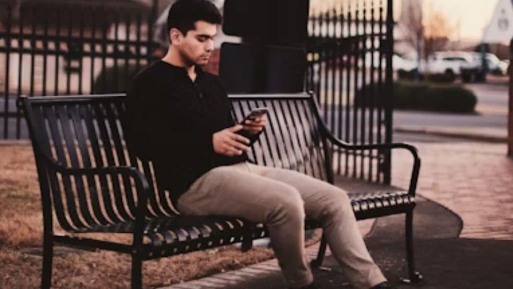 Man sitting alone, staring at his phone in confusion