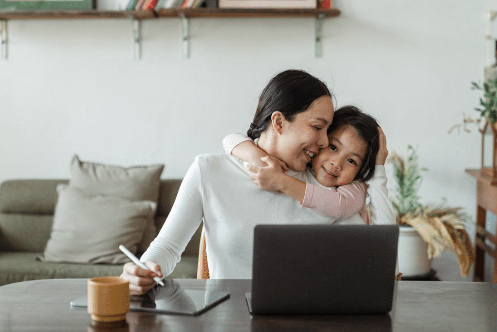 Cute little ethnic girl embracing working mother