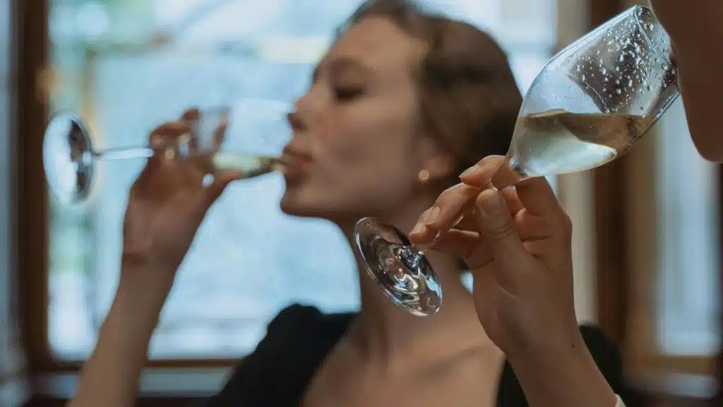 A woman drinking champagne from a glass.