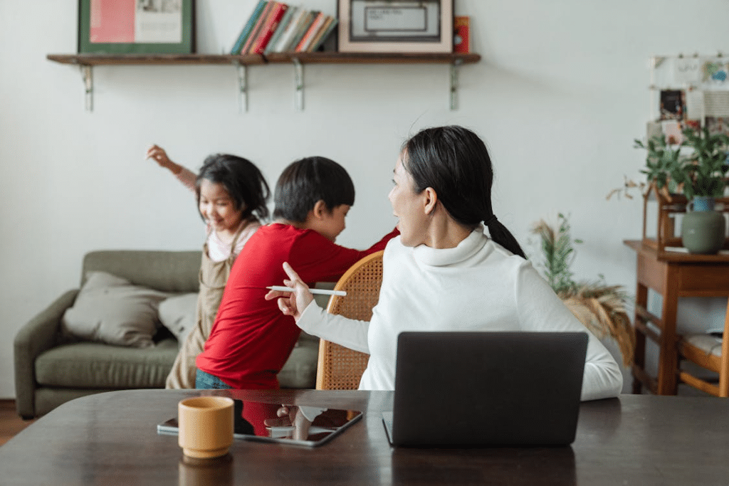 Young ethnic woman trying to work at home with active children