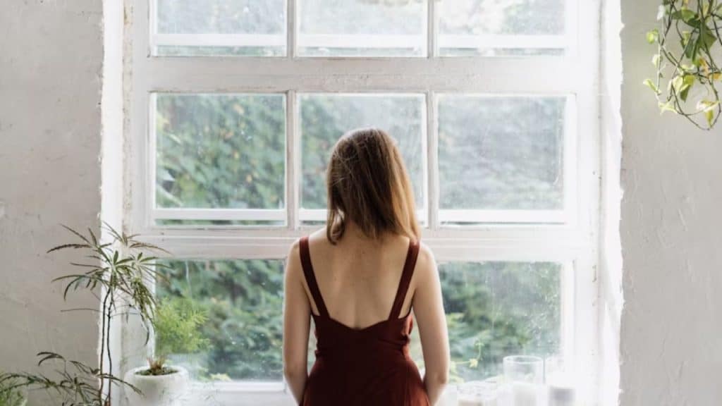 Woman looking out a window feeling empty