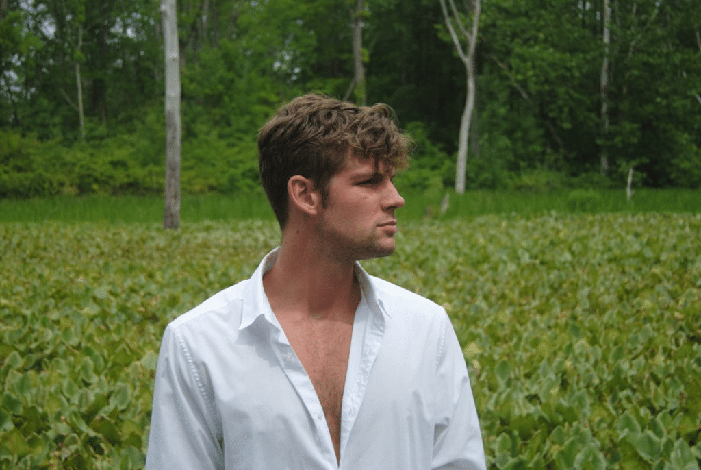 A Man in White Long Sleeves Standing on Green Grass Field