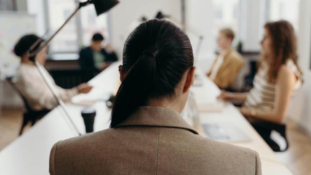 A woman sitting at a conference table facing a group of colleagues.
