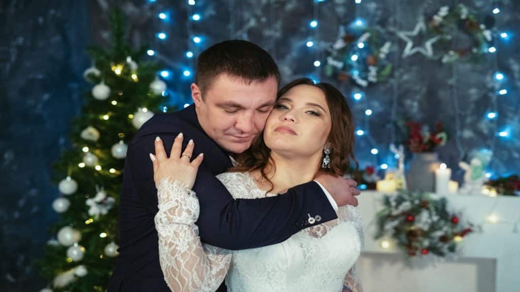 Man and woman hugging in front of the Christmas tree.