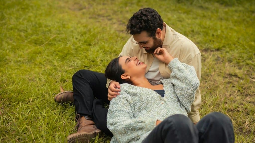 A woman lying with her head in her partnerβs lap and smiling at him.