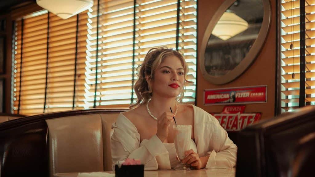A woman sitting in a diner drinking a milkshake.