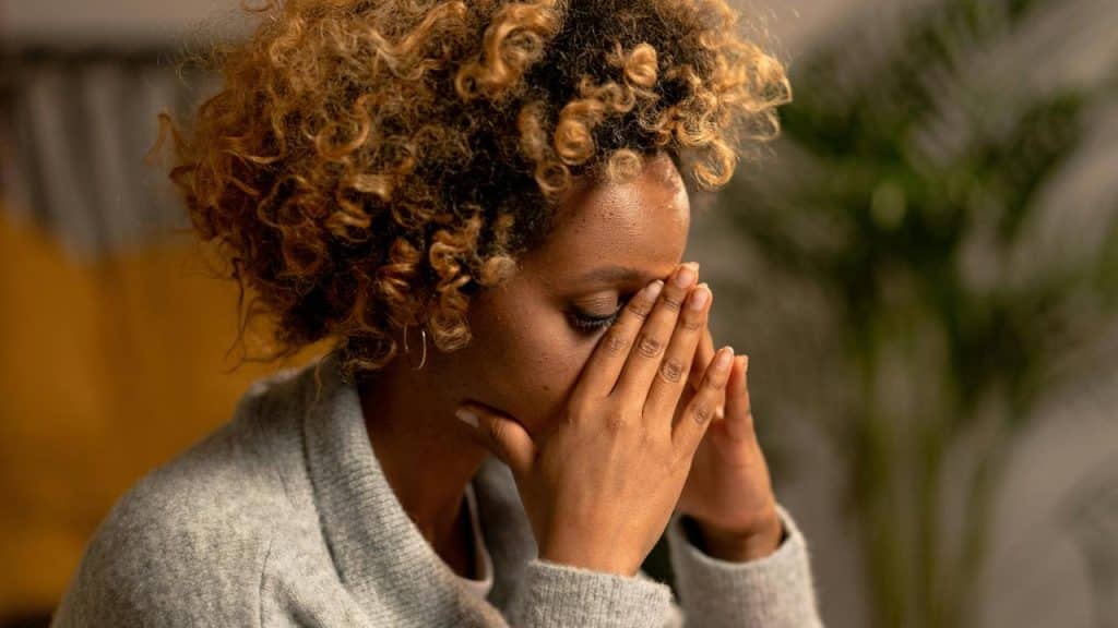 A woman sitting with her hands covering her face in frustration or stress.