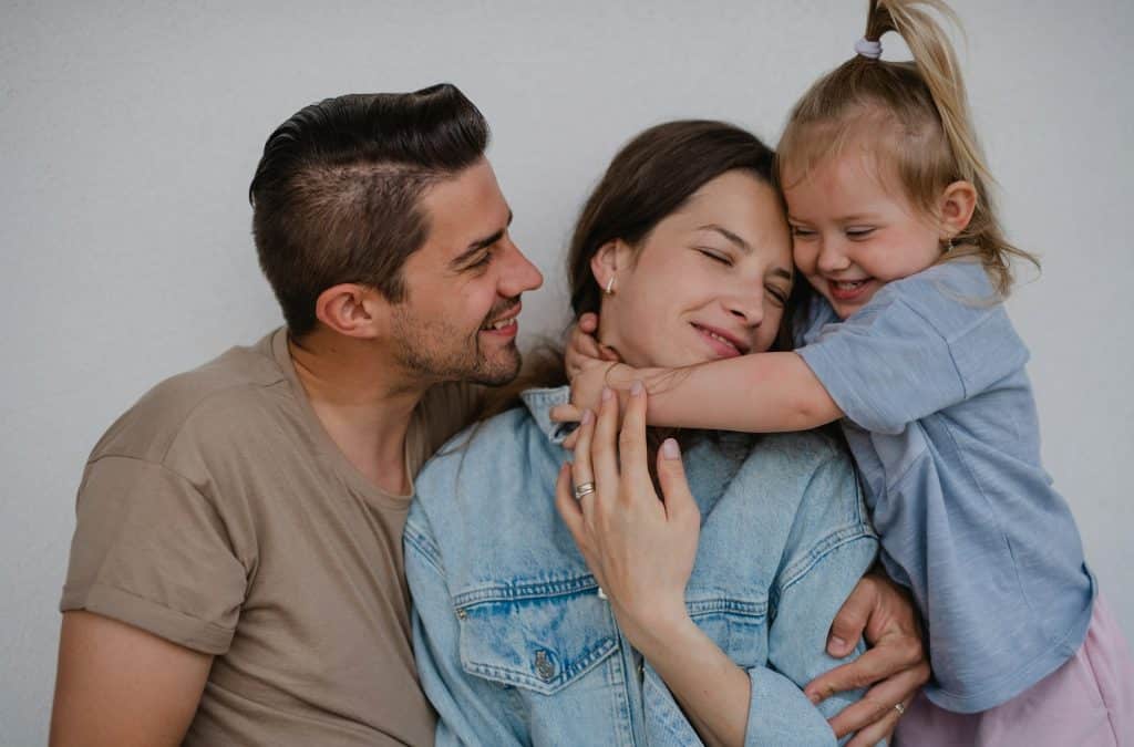 The man looks at her daughter while hugging her mom.