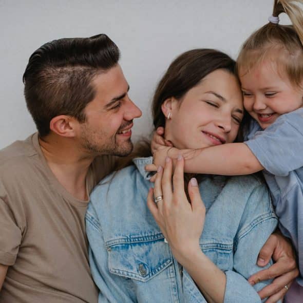 The man looks at her daughter while hugging her mom.