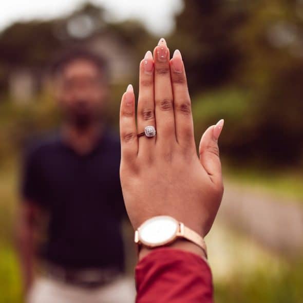 A woman’s hand and a man in the background.