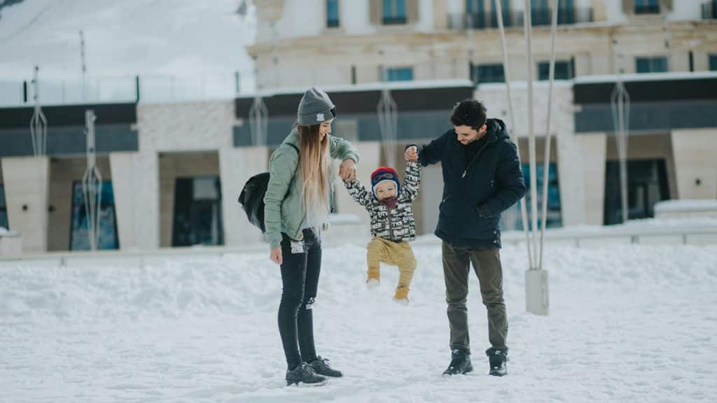 A couple playing with their kid in the snow.