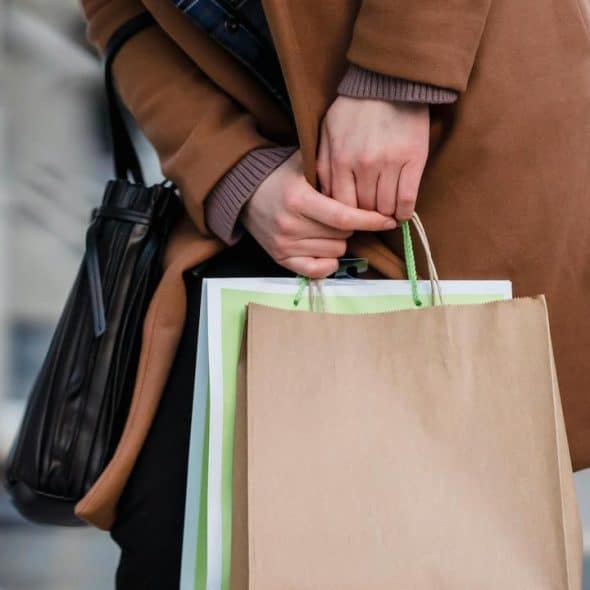 A person holding shopping bags while standing on a street.