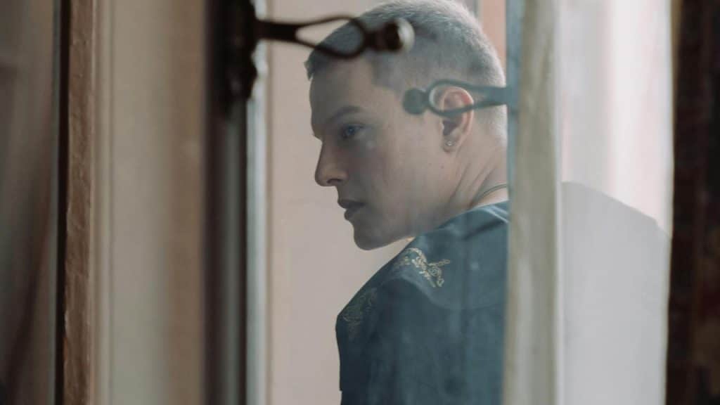 A person with short hair looking out a window.