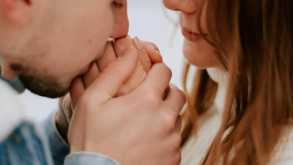 A man gently kissing a woman’s hand in a close-up moment.