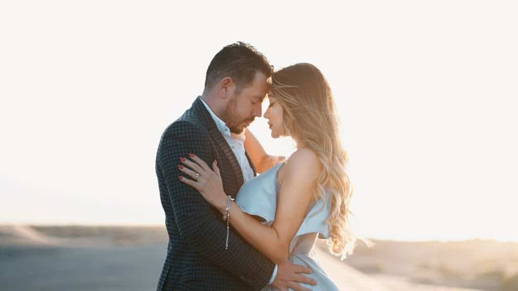 A man and a woman posing in a desert.