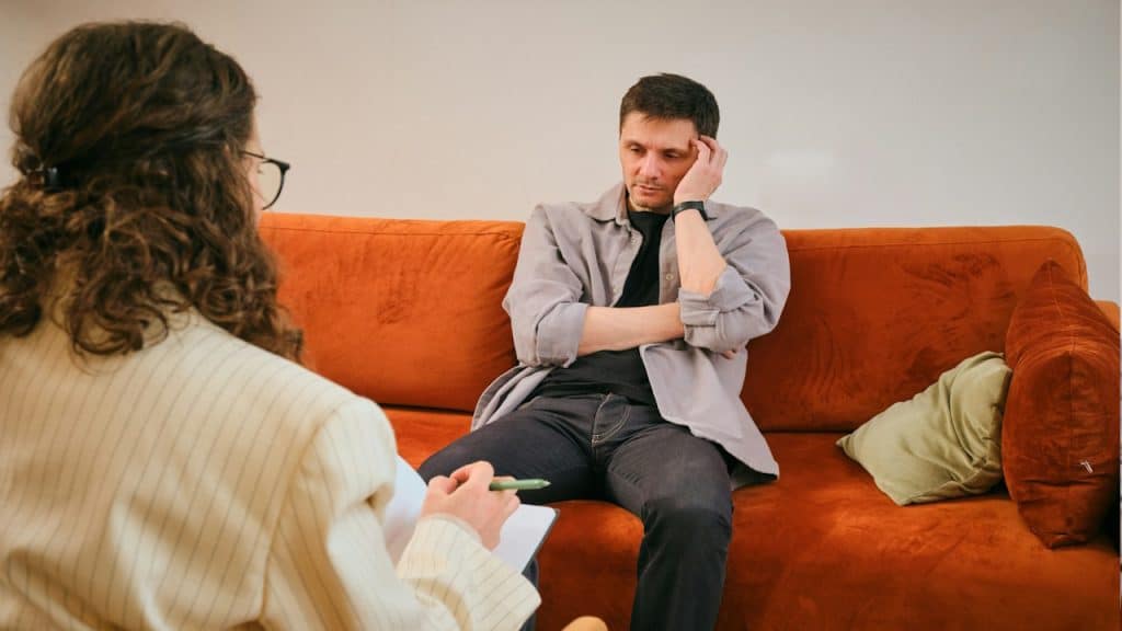 A man talking to his therapist while sitting on a sofa.