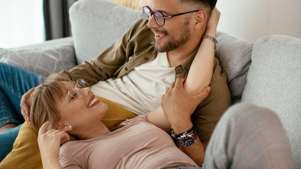 A couple relaxing on a couch and smiling at each other.