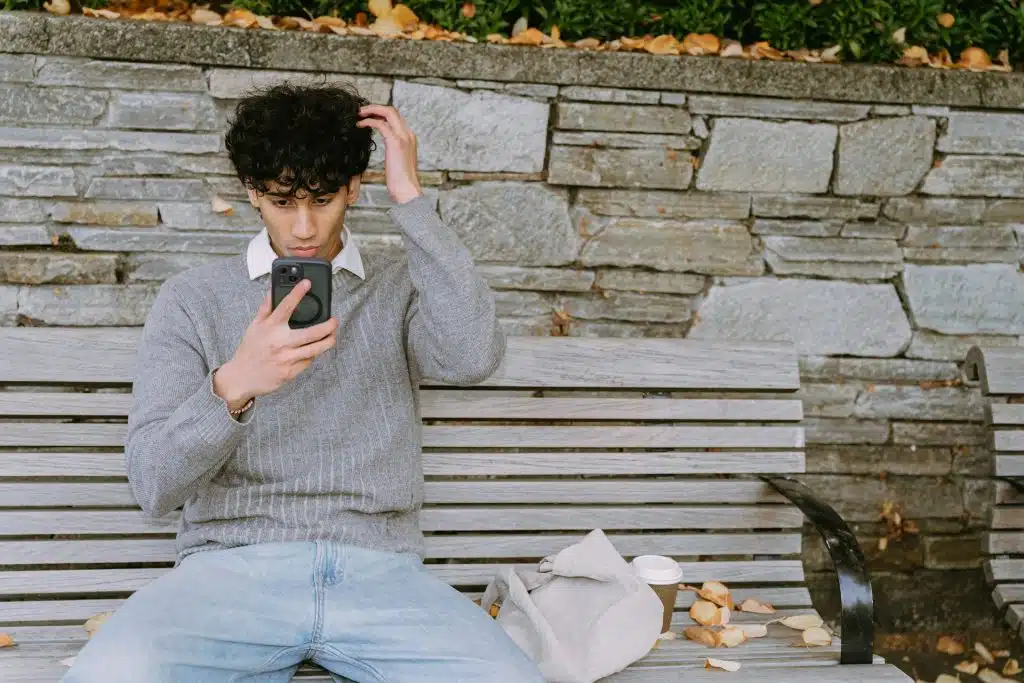 The man sitting on the bench is looking at his phone.