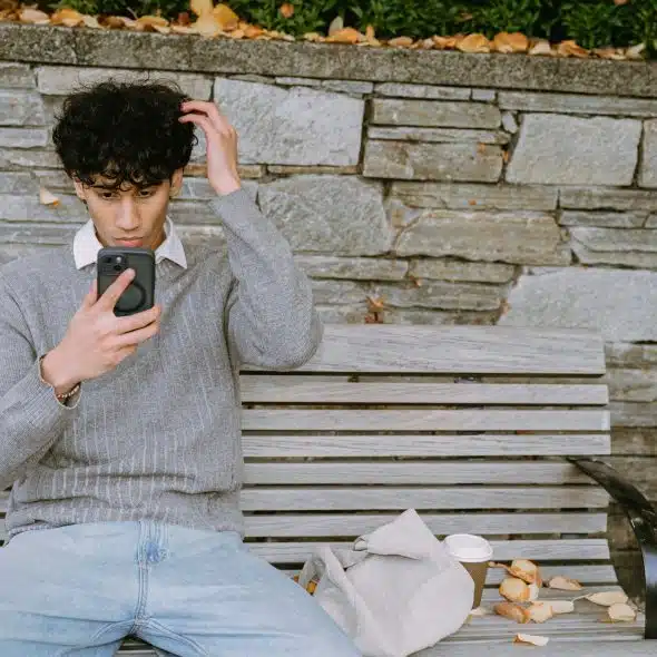 The man sitting on the bench is looking at his phone.