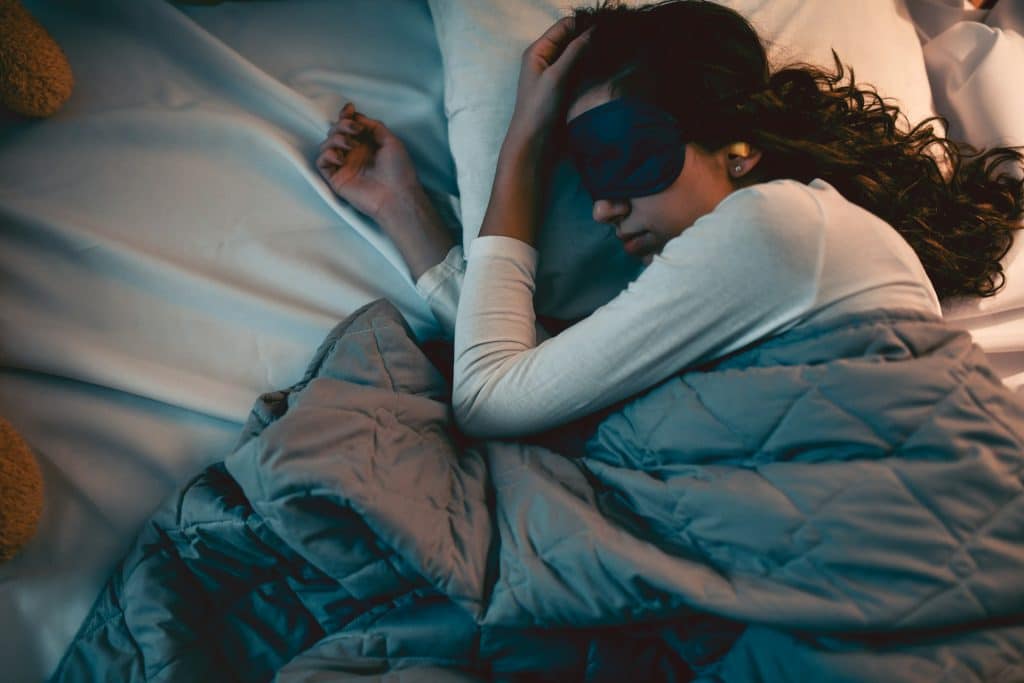 The woman is sleeping with a sleeping mask on her eyes.