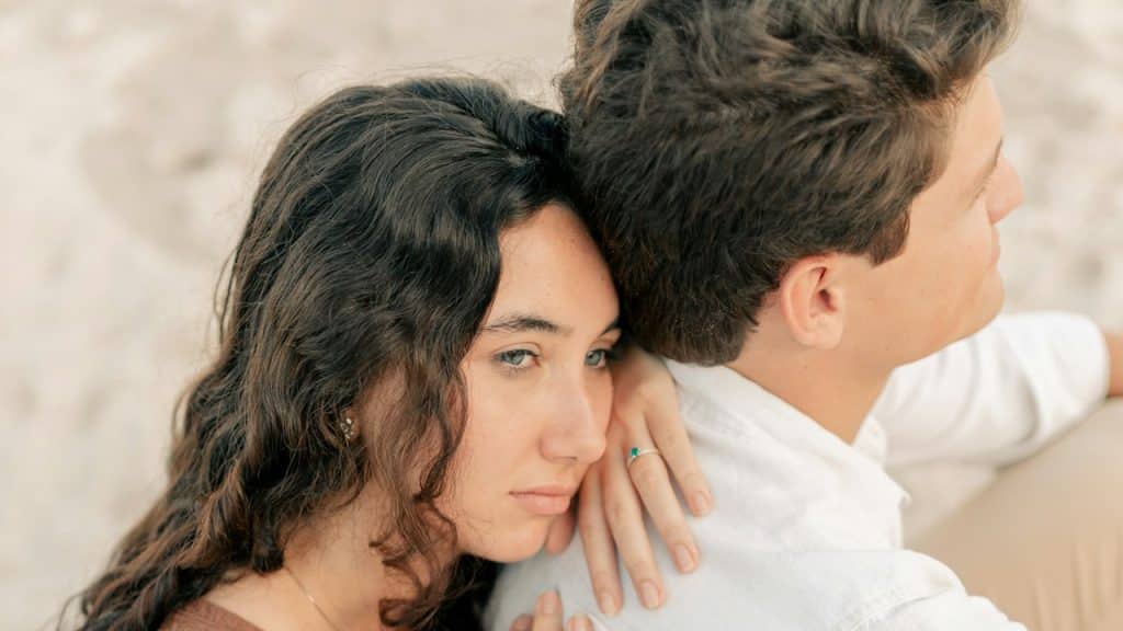 A man and a woman sitting on a beach.
