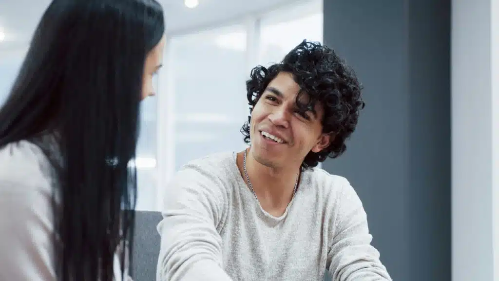 A man talking to a woman while smiling.