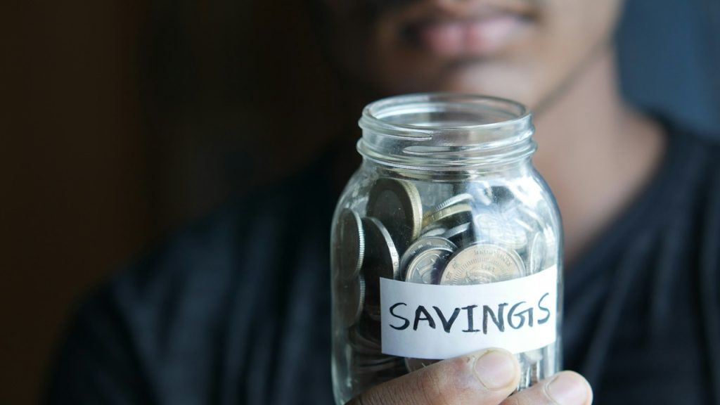 A man holding a jar with a savings label on it.