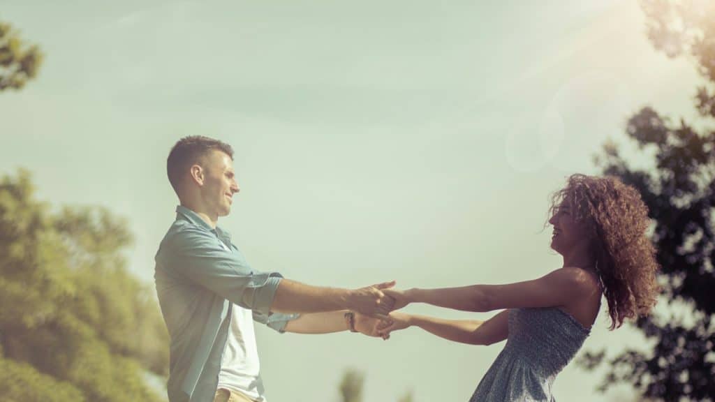A man and a woman holding hands in nature.