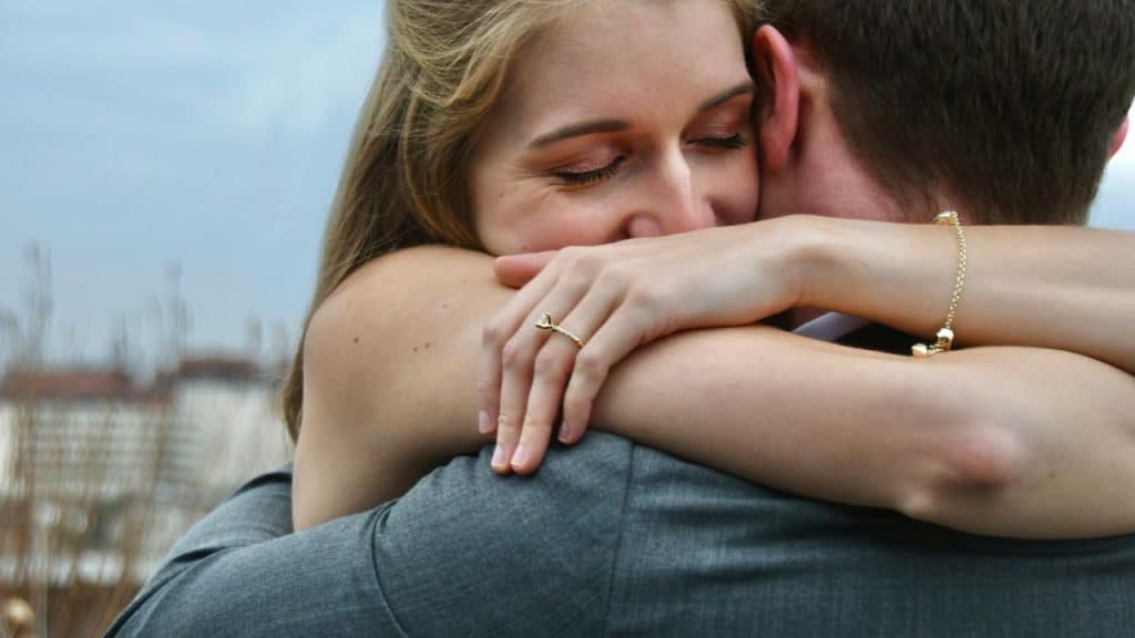 A woman hugging someone tightly with a relieved smile.