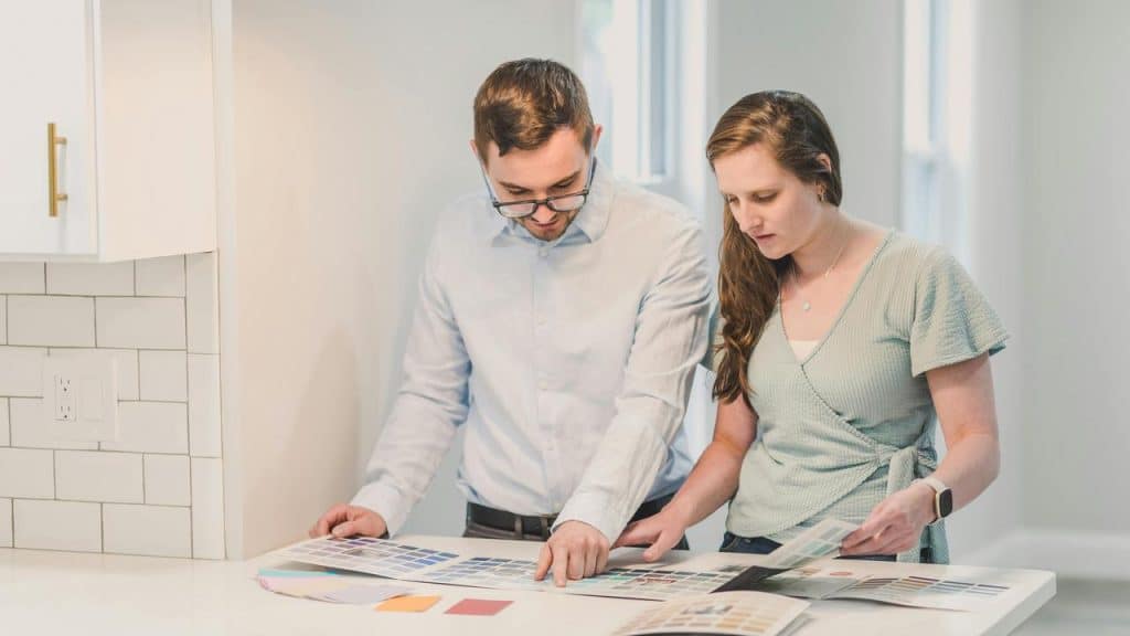 A man and woman reviewing color samples together in a bright kitchen.