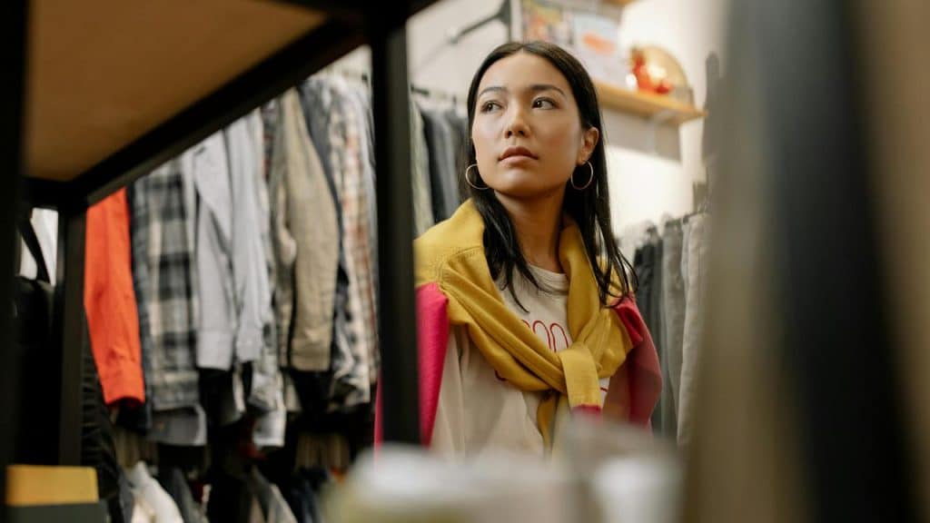 A woman standing in a clothing store looking at the racks of clothes.