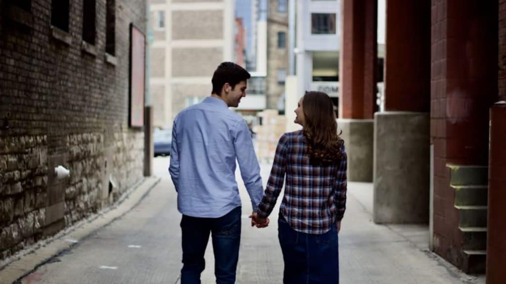 Couple walking hand in hand down a city