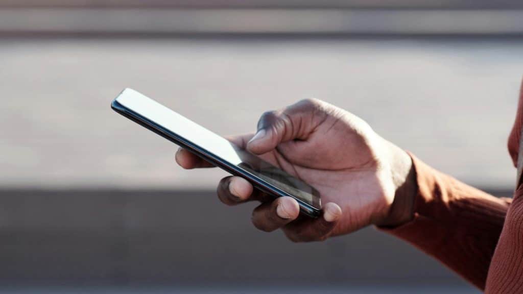 A person holding and using a smartphone outdoors.