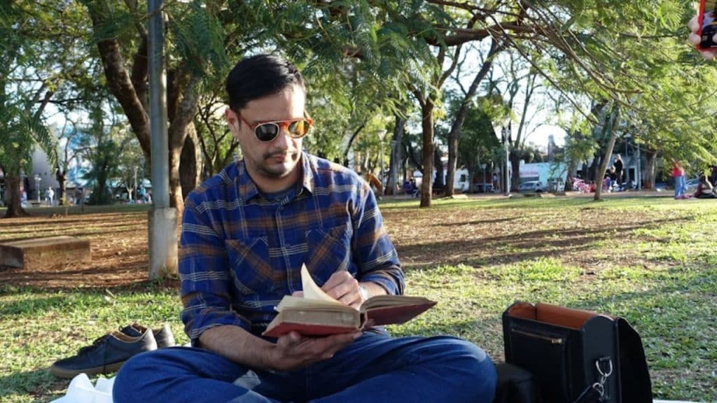 Man reading a book outdoors in a park