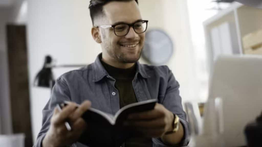 Man smiling while writing in a gratitude journal