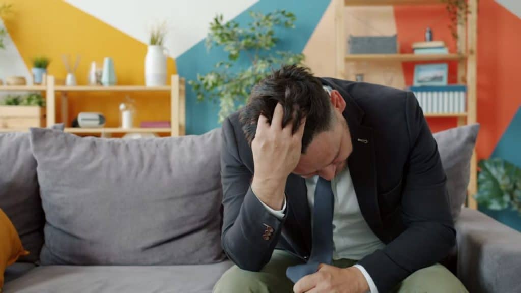 Man sitting on a couch  after an argument, looking tired
