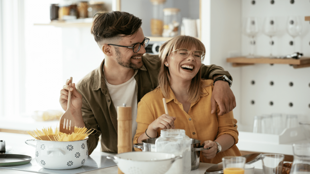 A couple laughing together while cooking