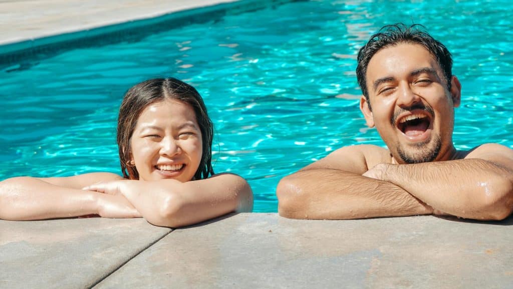 The man and the woman are smiling in the swimming pool.
