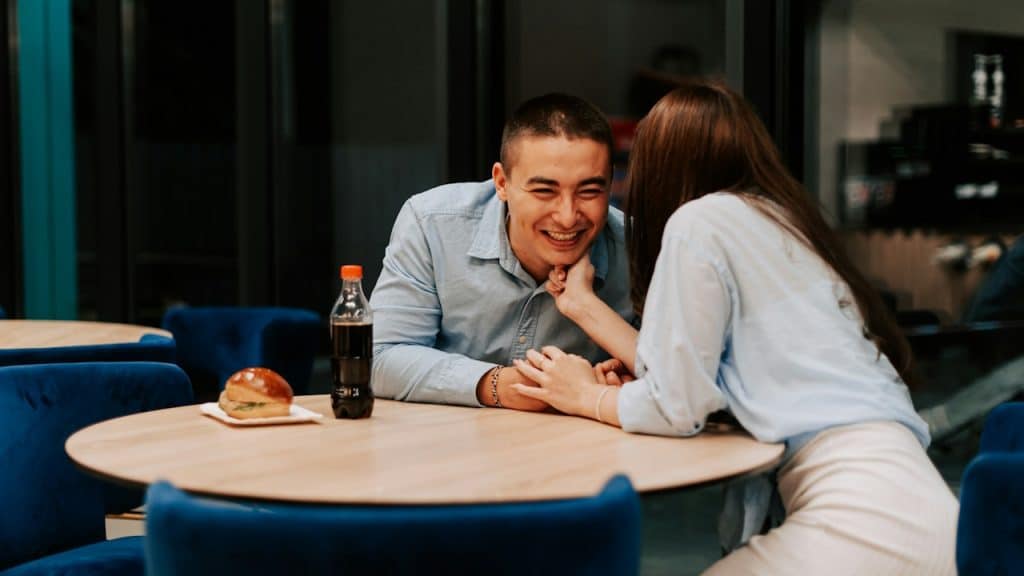 A woman whispering something in a man’s ear.