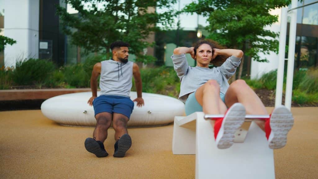 Woman doing exercise while man looking away.