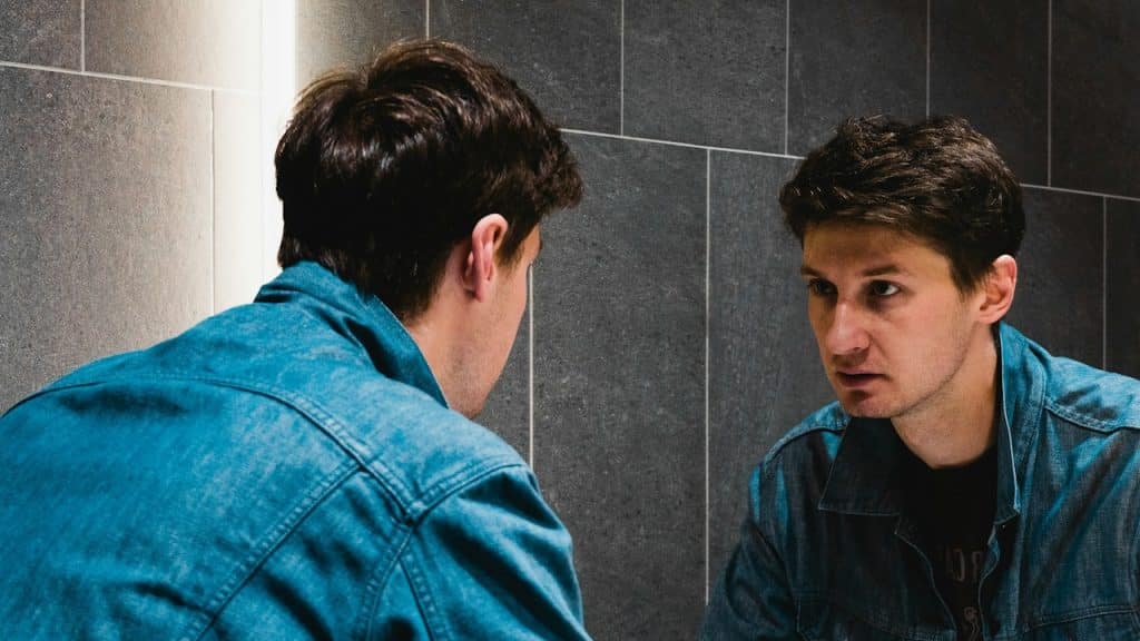 A man looking at himself in the mirror.