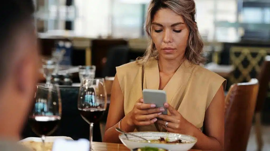 A woman looking at her phone while sitting at a restaurant table.
