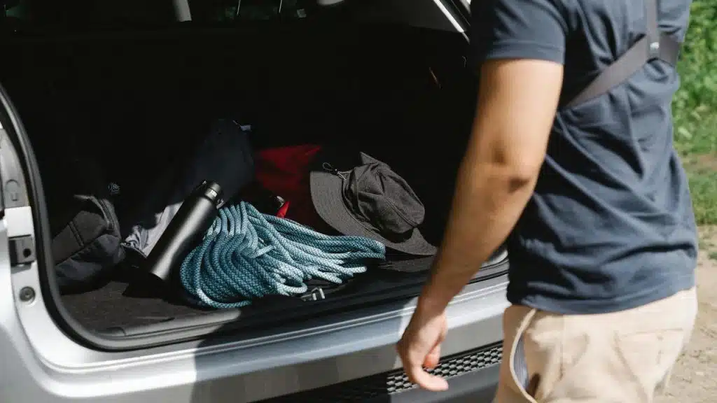 A person loading outdoor gear into a car trunk.