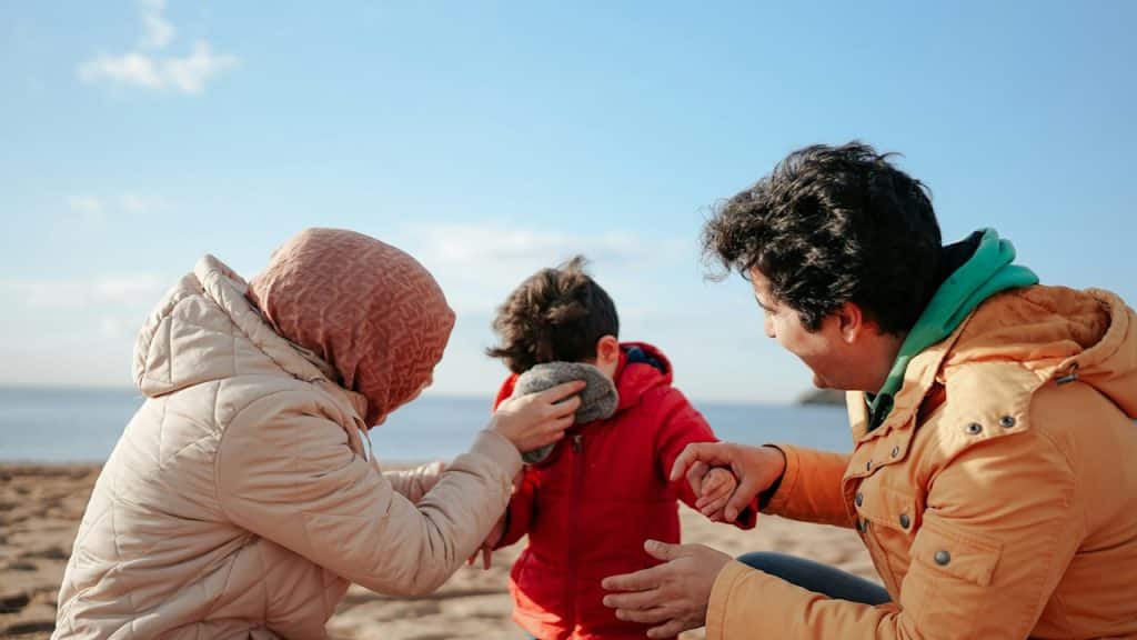 A man and a woman on a beach with their son.