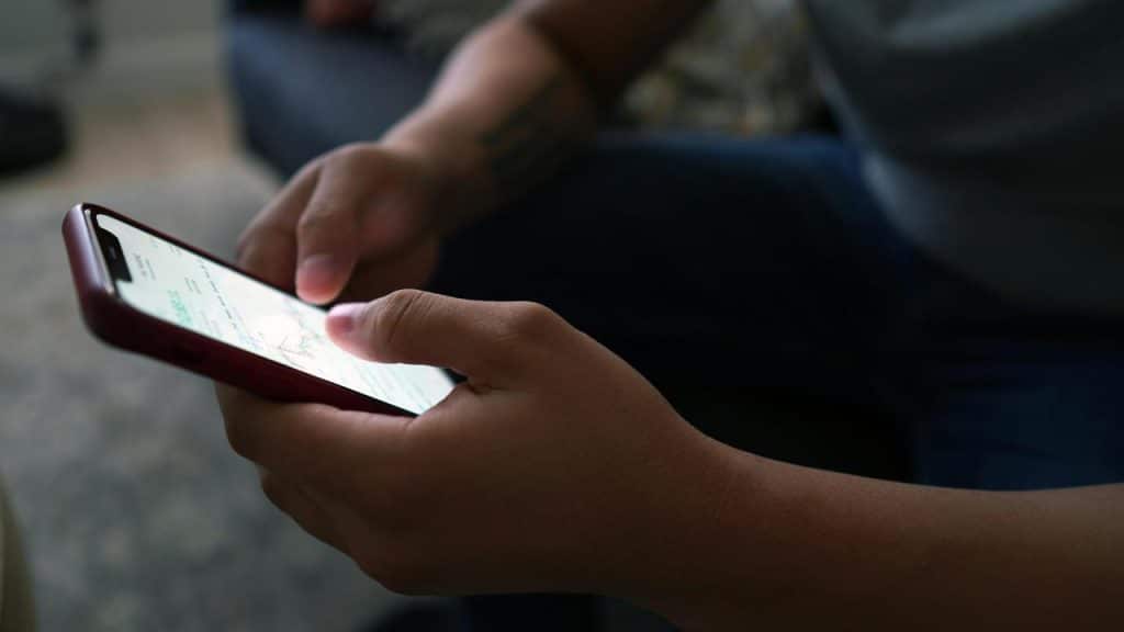 A close-up of hands holding a smartphone and scrolling.