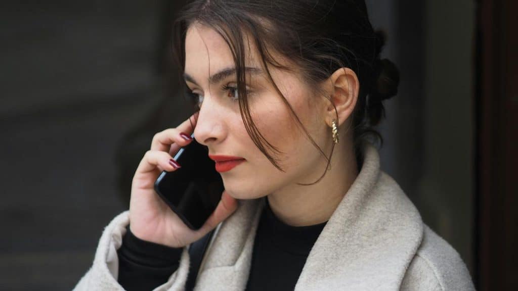 A woman talking on a smartphone while standing outside.
